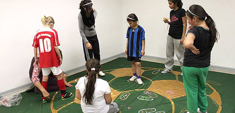 Mädchen stehen auf grünem Fußballteppich
